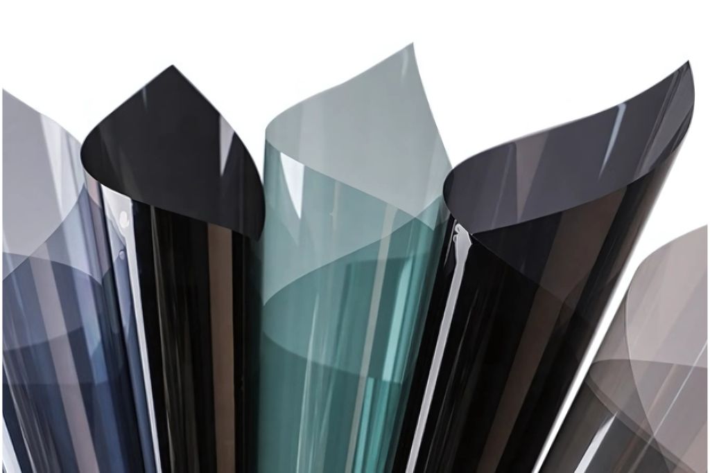 Several rolls of dyed window tint film in various shades of black and gray, showcasing the different levels of tint available. Dyed tints are an affordable option for reducing glare and absorbing solar heat.