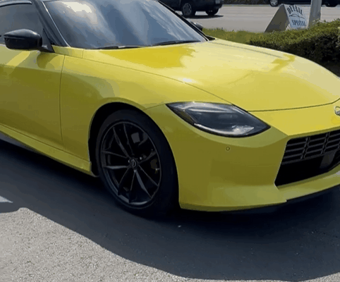 A yellow sports car with tinted windows parked outdoors, reflecting sunlight off its surface. The tint on the windows helps reduce glare and protect the car's interior.