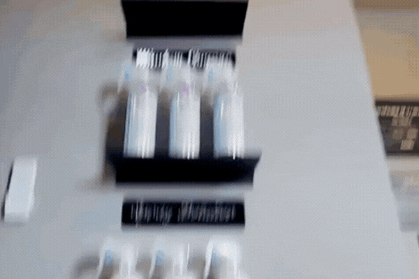 Animated GIF showing shelves stocked with various ceramic coating bottles and detailing products in a clean, professional shop setting. Labels highlight product categories like “Ceramic Coating” and “Detailing Chemicals.”