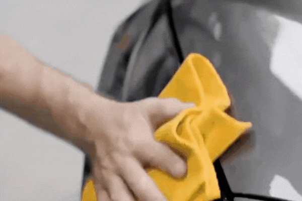 A hand uses a yellow microfiber cloth to gently buff the hood of a dark-colored car, revealing a smooth, reflective ceramic-coated finish. This image visually represents the high-quality service provided by Ceramic Coating Experts in Southampton, PA.