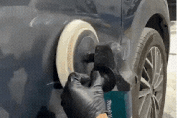 Why Remove Ceramic Coating — a close-up of a gloved hand using a polishing machine on a dark car panel in Southampton, PA to strip old ceramic coating before reapplication or paint correction