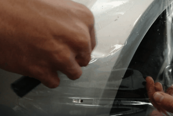 Professional installation of clear paint protection film on a red car hood at XP Automotive Restyling in Southampton, PA.