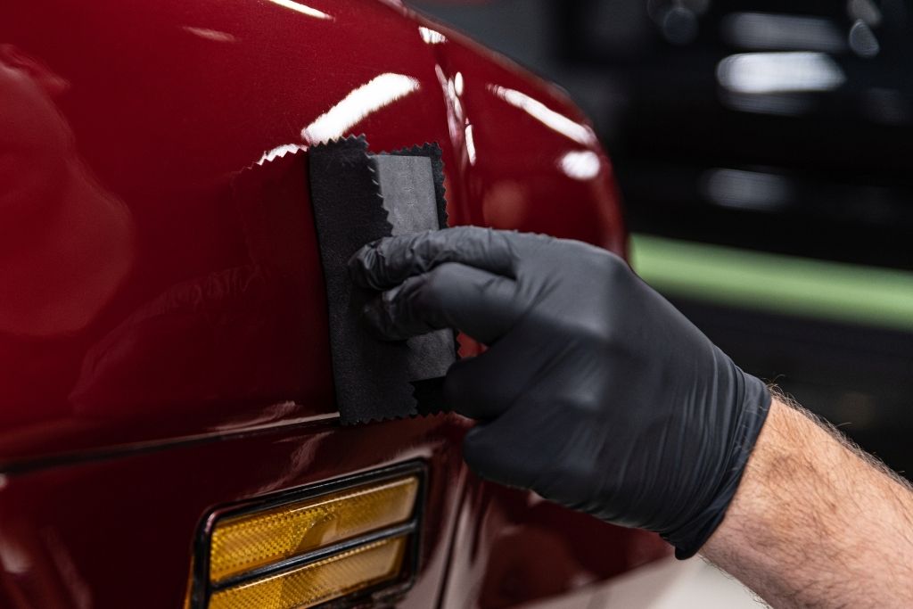 Technician applying ceramic coating to red car paint surface in Southampton PA for enhanced gloss and hydrophobic protection