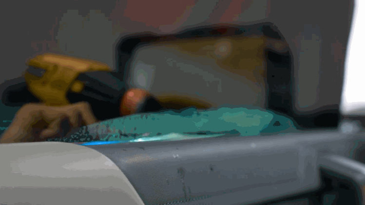 A blue window tint film laid across a car dashboard during installation. Tools and supplies sit nearby as the tint is prepared for a vehicle window.