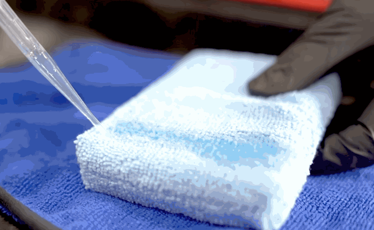 Ceramic coating liquid is poured onto a microfiber applicator towel before being applied to a vehicle.
